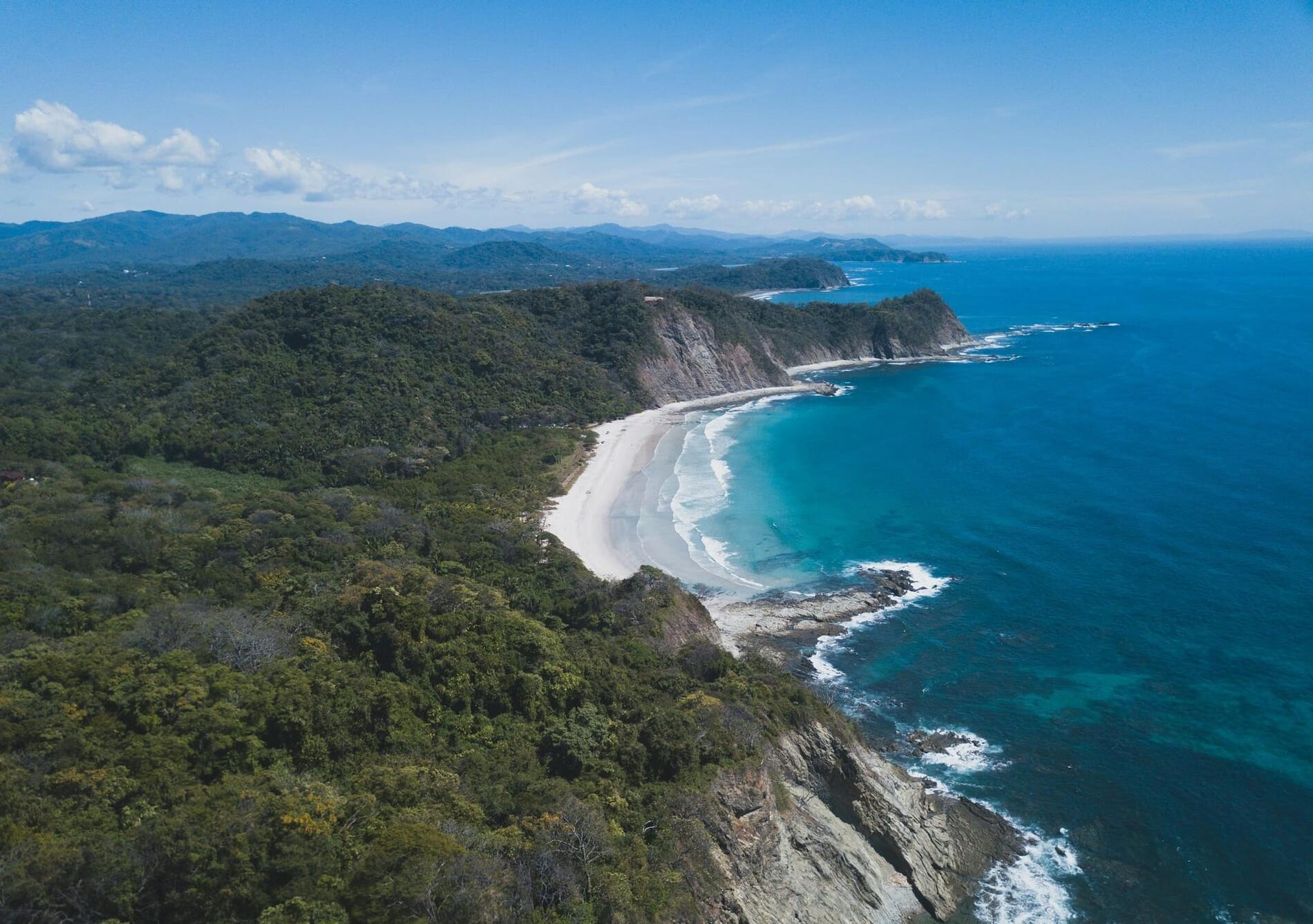 Aerial view of Guanacaste's Gold Coast — jungle cliffs meeting the Pacific near Sámara, Costa Rica